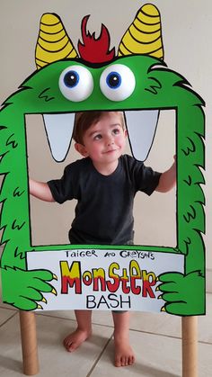 a young boy standing in front of a monster photo frame