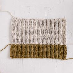 a white and brown knitted dishcloth hanging from a hook on a white wall