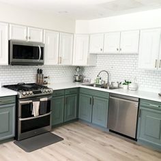 a kitchen with green cabinets and stainless steel appliances in the center, white subway backsplash