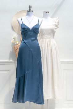 two women's dresses on mannequins, one in blue and the other in white