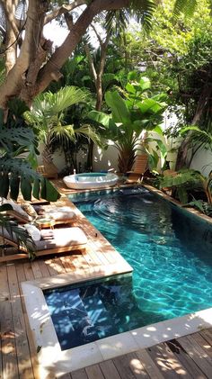 an outdoor swimming pool surrounded by greenery and wooden decking with lounge chairs around it