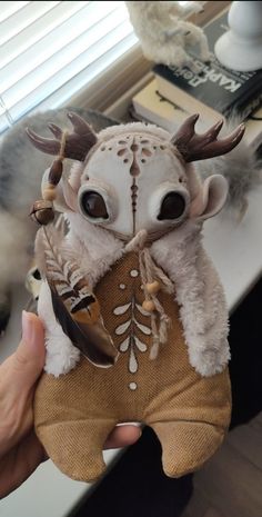 a stuffed animal with antlers on it's head is held up in front of a window