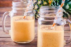 two mason jars filled with smoothies next to a pineapple