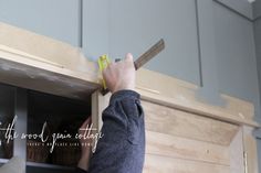 a person is measuring the width of a piece of wood on top of a cabinet