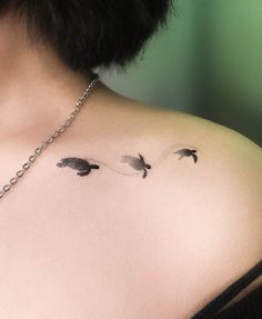 the back of a woman's shoulder with three small birds on her left side