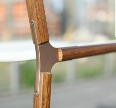 a close up of a wooden handle on a metal railing with buildings in the background