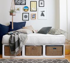 a bed with baskets underneath it and pictures on the wall