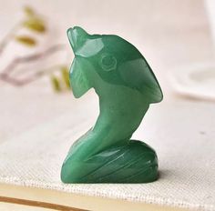 a green glass figurine sitting on top of a book