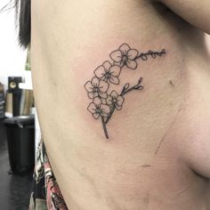 a woman's stomach with a small flower tattoo on her left side ribcage