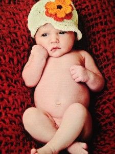 a baby is wearing a crocheted hat with flowers on it