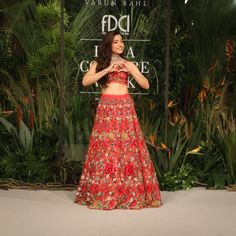 a woman in a red dress standing on a runway