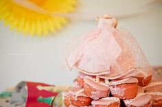 a tower of cupcakes with pink frosting on top and a veil over the top