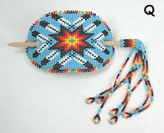 a beaded object with a wooden stick and string attached to it, sitting on a white surface