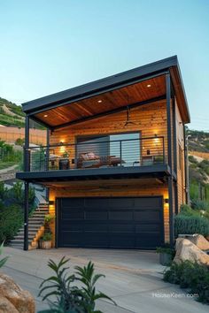 a house with a garage in front of it on top of a hill next to some rocks