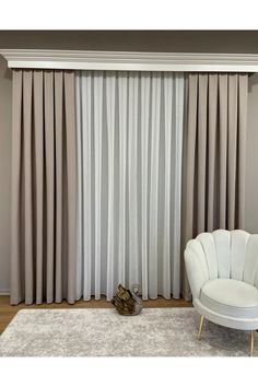 a white chair sitting in front of a window with curtains hanging on the wall behind it