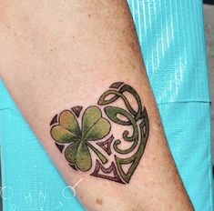 a heart shaped tattoo with four leaf clovers on the side of its arm,