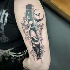 a person with a tattoo on their arm holding a knife and skull in front of them