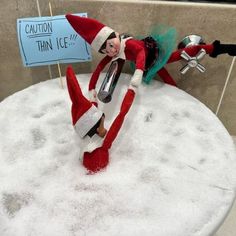 an elf laying on top of a pile of snow next to a sign that says caution thin ice