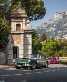 two classic sports cars driving down the road