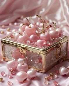 a small box filled with pink beads and cherries on top of a table cloth