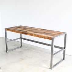 a wooden table sitting on top of a white floor next to a metal framed wall