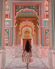 a woman in a striped dress walking through an ornate building