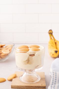 a dessert dish with cookies and cream in it on a wooden board next to bananas