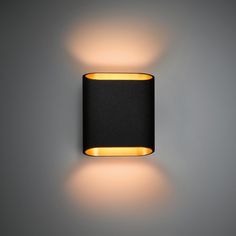 a wall light that is on the side of a wall, with a black shade