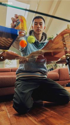 a man is sitting on the floor with tennis rackets and balls in his hands