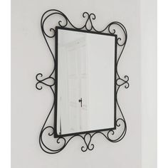 a mirror hanging on the wall with an iron frame and scroll work around it's edges