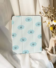 an ipad case sitting on top of a bed next to flowers