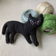 a black cat figurine next to balls of yarn