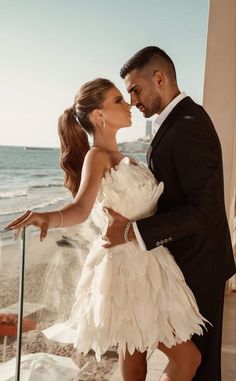 a man and woman standing next to each other near the ocean