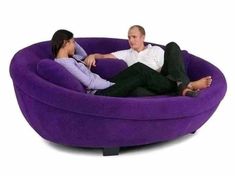 a man and woman sitting in a purple bean bag chair with their feet on the ground