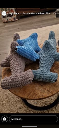 there are three knitted stars on top of a wooden table, one is blue and the other is gray