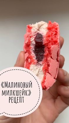 a hand holding a piece of red and white cake