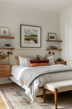 a white bed sitting next to a wooden dresser under a framed picture on the wall