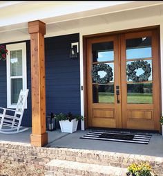 front porch with rocking chair and wreaths on the door way to a blue house