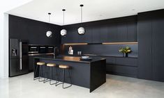 a modern kitchen with black cabinets and stools in front of an island countertop