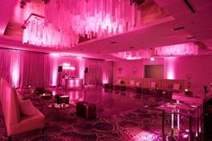 a room filled with lots of furniture and pink lighting