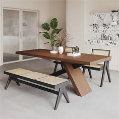 a dining room table with two benches and a plant in the corner next to it