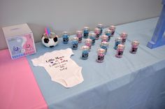 a baby shower is set up on a blue tablecloth with pink and white decorations