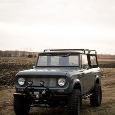 an old jeep is parked in the middle of a field with no one around it