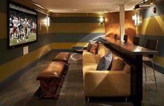 a home theater room with couches and a large screen tv on the wall above it