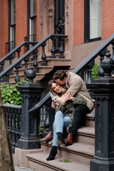 a man and woman sitting on the steps of an apartment building with their arms around each other