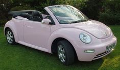 a pink convertible car parked in the grass