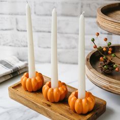 three candles are sitting on a tray with pumpkins