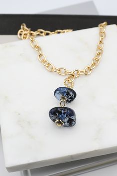 This elegant necklace features two ocean blue resin beads on a gold-plated chain. The light-catching surface of the beads offers an additional hint of luxury to the wearer. With its timeless design and luxurious materials, it's the perfect accessory to any outfit.Details: Gold Chain Necklace Drop Feature with Two Blue Resin Beads Approximate Dimensions: Length: 18.0" Drop Feature Length: 2.75" Small Blue Bead: 1.0" x 0.4" Large Blue Bead: 1.25" x 0.5" Elegant Necklace, Resin Beads, Elegant Necklaces, Gold Chain Necklace, Ocean Blue, Blue Beads, We Wear, Outfit Details, Body Oil