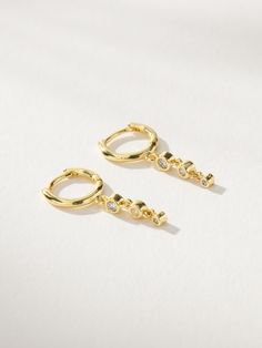 Our City Lights Huggie Earrings may be dainty, but they definitely don’t lack any sparkle. Crafted from a mini gold hoop and a sparkly dangle, these huggie earrings are sure to complete any silver or gold look. If you want an ear stack that really shines, be sure to layer these huggies with anything from our Just Add Sparkle Collection. Gold Dangle Huggie Earrings For Party, Gold Sparkling Minimalist Earrings, Minimalist Sparkling Gold Earrings, Party Dangle Huggie Earrings, Gold City, Huggie Earrings Gold, Ear Stack, Gold Hoop, Jewelry Cleaner