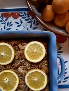 there are lemons on top of the food in the dish and some oranges next to it